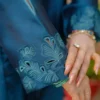 Close-up of Teal Blossom Ladies Dress on model, focusing on floral embroidery details, from Saanah traditional wear collection.