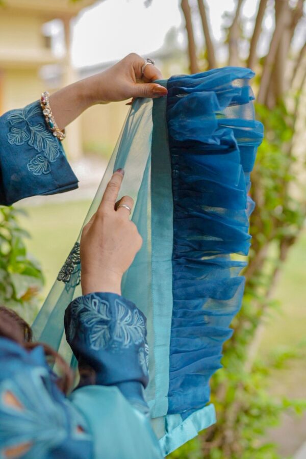 Close-up of Teal Blossom Ladies Dress on model, focusing on floral embroidery details, from Saanah traditional wear collection.