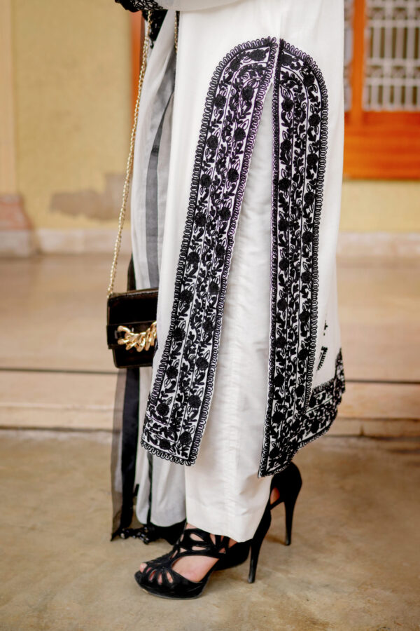 Model wearing Shan-e-Zar: White Elegance Unleashed, highlighting back design with floral embroidery, from Saanah traditional wear collection.
