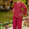 Front view of a woman wearing the Saanah Maroon Elegance Tailored Coord Set in vibrant maroon with floral sleeves, standing in a garden at night.