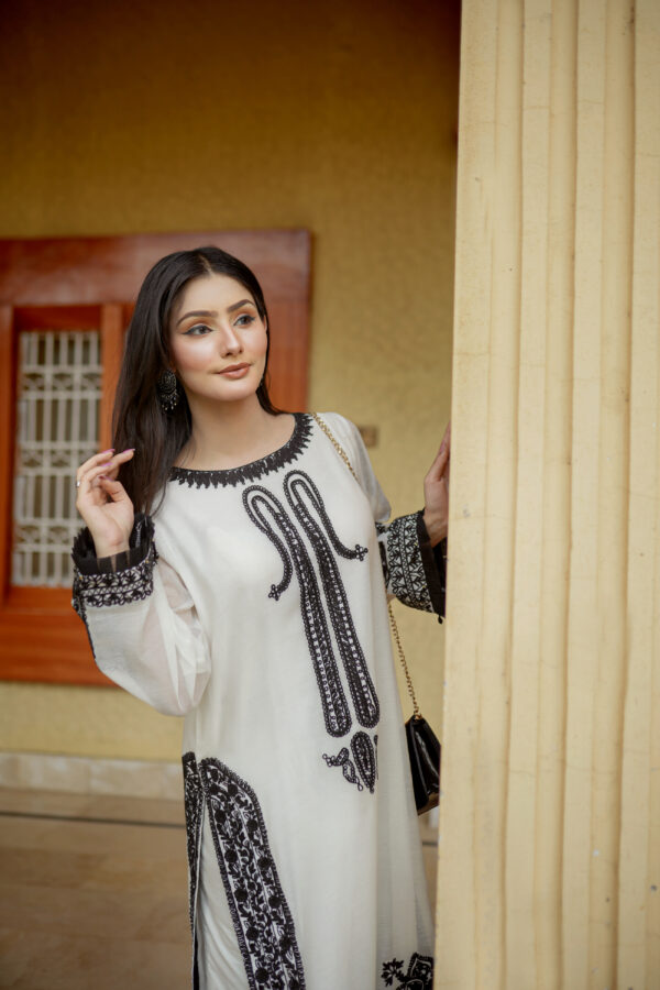 Model posing elegantly in Shan-e-Zar: White Elegance Unleashed, a white traditional dress, from Saanah traditional clothing collection.