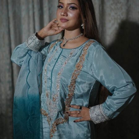 Side profile of a woman wearing the Saanah Frosted Elegance Russian Silk Suit in ice blue, highlighting the embroidered neck and scalloped organza dupatta indoors.