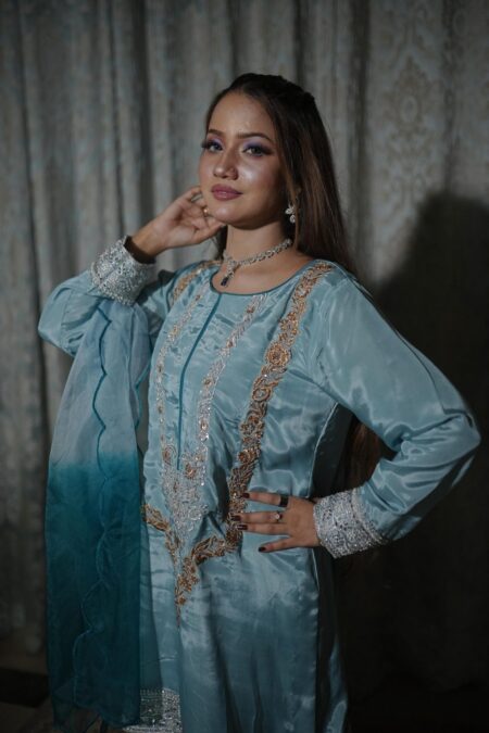 Side profile of a woman wearing the Saanah Frosted Elegance Russian Silk Suit in ice blue, highlighting the embroidered neck and scalloped organza dupatta indoors.